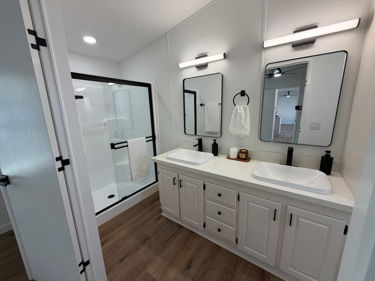 Renovated mobile home bathroom with dual vanity and glass shower